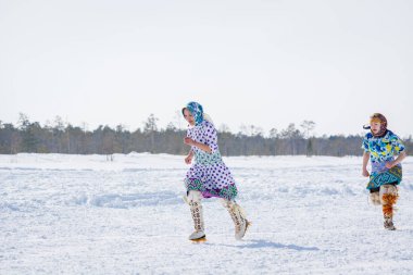 Russkinskaya, Rusya - 24 Mart 2018: Kuzey deki ulusal giyimli iki Hanty kadını kışın çapraz koşuyor. Kızlar arasındaki rekabet. Reindeer çobanları günü bayramı.