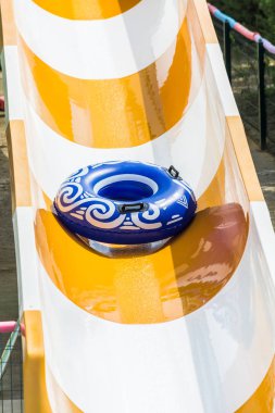 Side, Turkey - June 2018: Blue tubing rolls down a water slide in a water park. clipart