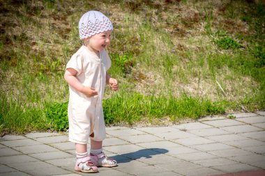Nehir limanının rıhtımından asfalt yolun etrafında koşan beyaz takım elbiseli küçük bir çocuk.