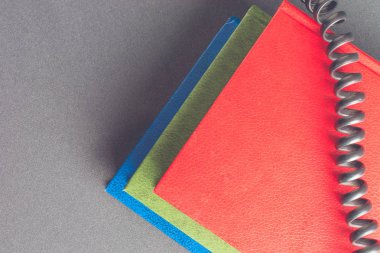 Bükülmüş telefon teli renkli kitap yığını üzerinde yatıyor