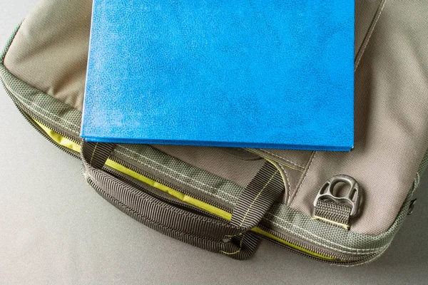 Blue book lies on a laptop bag