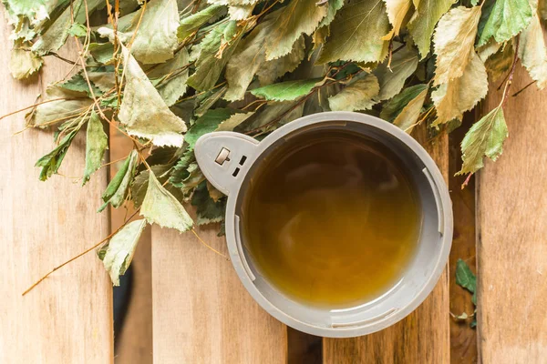 Thé chaud dans une tasse d'un thermos avec un balai de bouleau dans un bain — Photo