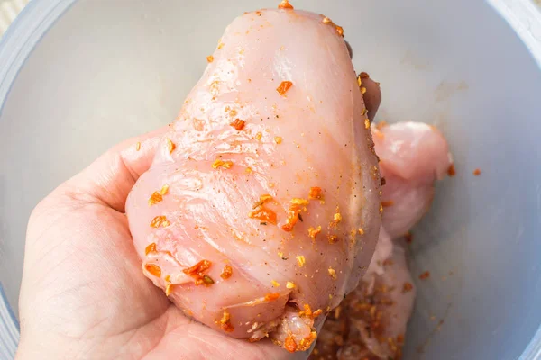 Frango cru esfregado com especiarias picantes na mão masculina sobre prato grande . — Fotografia de Stock