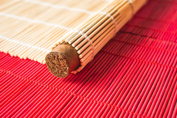 Великолепная сигара, завернутая в квадратный бамбуковый коврик . — стоковое фото