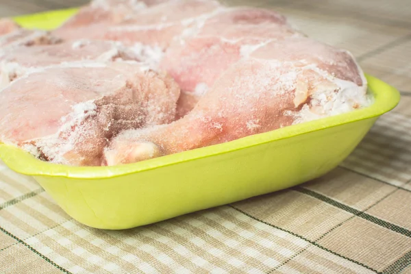 Patas de pollo congeladas para cocinar en recipiente de plástico verde en la mesa de la cocina . — Foto de Stock