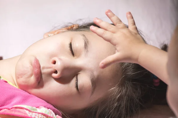 Kleines Kind legt seine Hand auf den heißen Kopf der geduldigen Schwestern — Stockfoto