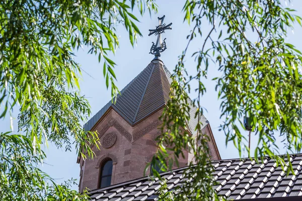 Antigua iglesia armenia con una gran cruz junto al árbol verde contra el cielo azul — Foto de Stock