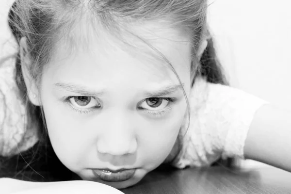 La chica enojada no quiere hacer la tarea acostada sobre la mesa. —  Fotos de Stock