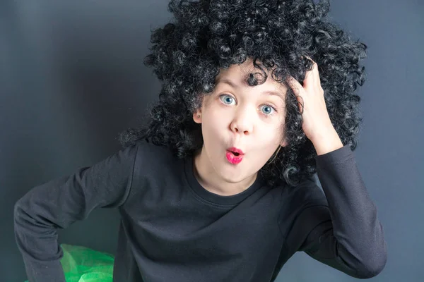 stock image Beautiful girl in a black curly wig poses a monkey