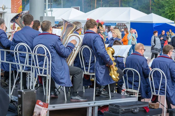 スルグト、ロシア - 2018年9月2日:女性指揮者がパイプとサックスを演奏する男女の交響楽団を指揮します。石油・ガス産業の休日労働者. — ストック写真