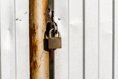 Demir kapıda asılı kapalı asma kilit.