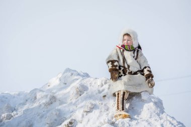 Russkinskaya, Rusya - 24 Mart 2018: Sibiryalı çocuk, orta meydandaki kar dağının üzerinde, geyik derisi ve kürkten yapılmış ulusal kuzey giysili. Reindeer çobanTatil.