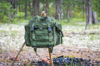 Spor ve rekreasyon için küçük bir sırt çantası, yangın ve dinlenme için yer yakın ormanın kenarında iki ahşap sopa üzerinde asılı