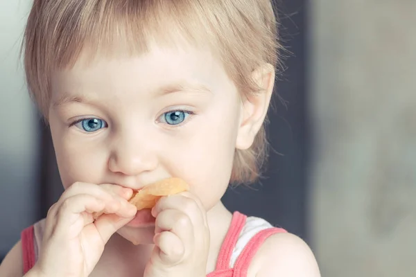 Солодка дівчина з великими блакитними очима їсть апельсиновий шматочок . — стокове фото