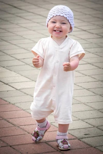 Un petit enfant en costume blanc qui court autour du chemin pavé depuis le quai du port fluvial — Photo