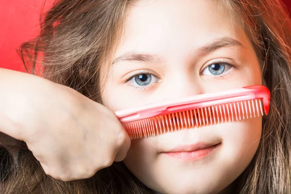 Красива дівчина розчісує вуса на червоному тлі — стокове фото
