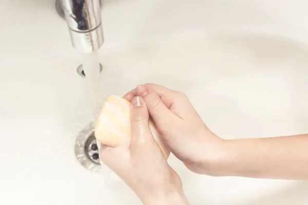 Child washing hands with soap and water.