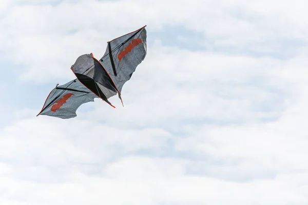 A beautiful bat shaped kite is flying in the clouds. Royalty Free Stock Photos