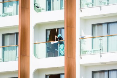 Side, Turkey - 5 Haziran 2018: Otel temizlikçisi balkondaki camları yıkıyor.
