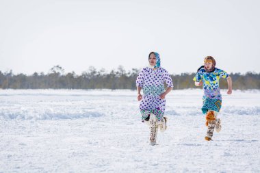 Russkinskaya, Rusya - 24 Mart 2018: Kuzey deki ulusal giyimli iki Hanty kadını kışın çapraz koşuyor. Kızlar arasındaki rekabet. Reindeer çobanları günü bayramı.