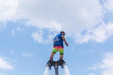 Side, Türkiye - 1 Haziran 2018: Yakışıklı tabaklanmış adam sineklikte duruyor ve bulutlarla mavi gökyüzüne uçuyor.