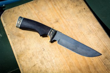 Tahta üzerinde siyah saplı demir bir bıçak..