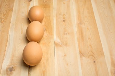 Üç tavuk yumurtası tahta bir tahtanın üzerinde yatıyor.