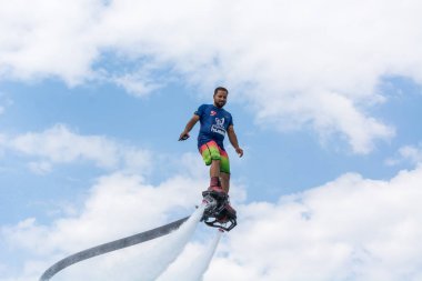 Side, Türkiye - 1 Haziran 2018: Yakışıklı tabaklanmış adam sineklikte duruyor ve bulutlarla mavi gökyüzüne uçuyor.