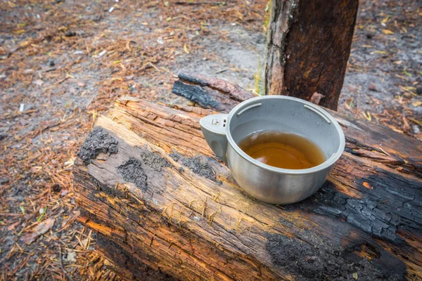 Tasse thermos en plastique avec thé chaud sur bois brûlé . — Photo