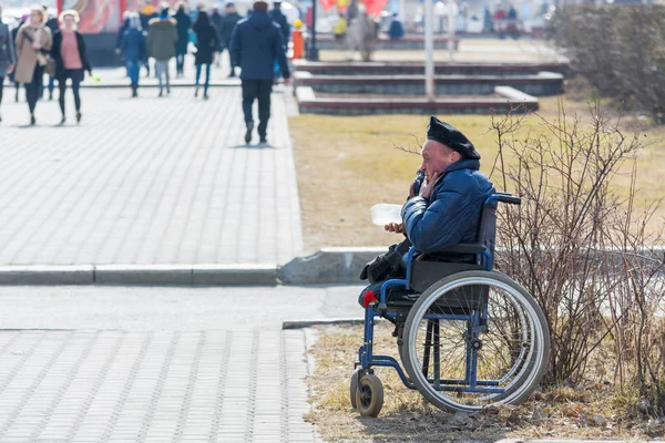 Surgut, Rusya - 9 Mayıs 2018: Arabada bere savurarak askeri engelli kişi yoldan geçenlerden para istiyor. Tatil Zafer Bayramı 9 Mayıs.