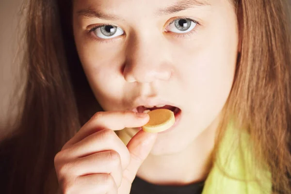 Ziek meisje met groene sjaal neemt grote gele pil van ziekte in de mond. — Stockfoto