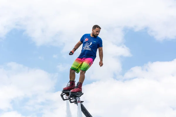 SIDE, TURCHIA - 1 GIUGNO 2018: Il bell'uomo abbronzato sta sul flyboard e vola contro il cielo blu con le nuvole . — Foto Stock