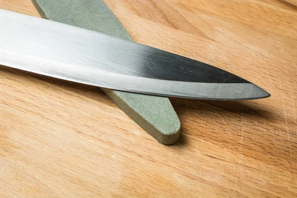 Estúpido cuchillo de cocina para verduras con muela de abrasivo grueso sobre tabla de madera . —  Fotos de Stock