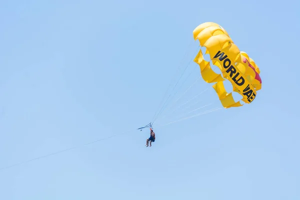 SIDE, TURKEY - MAY 31, 2018: Yellow parachute with tourists flies in sky tied to boat. — Stock Photo, Image