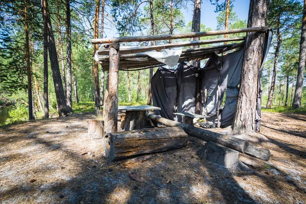 Wooden hut with table and logs in the forest by the river. — 스톡 사진