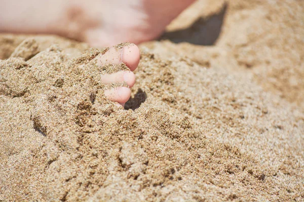 Babyfüße stecken an sonnigem Tag im Sand am Strand. — Stockfoto
