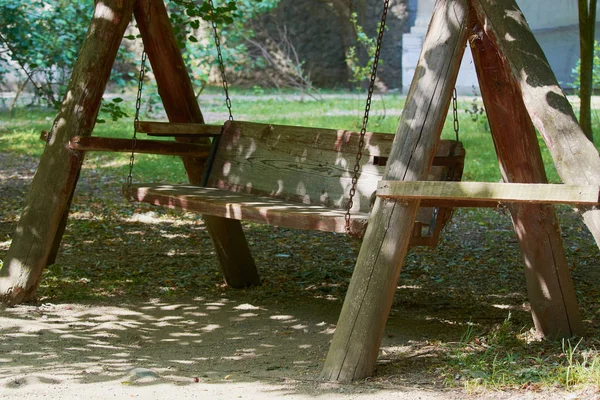 Old wooden swing on an iron chain in park