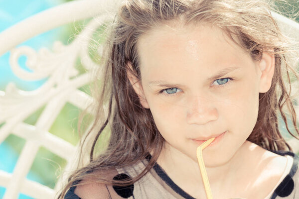 Beautiful girl in summer black dress holding drinking tube in her lips on sunny day