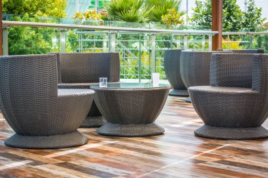 Wicker table with chairs for rest on the top floor against the background of green trees