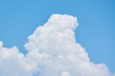 Kabarık beyaz bulutlar mavi gökyüzünde asılı.