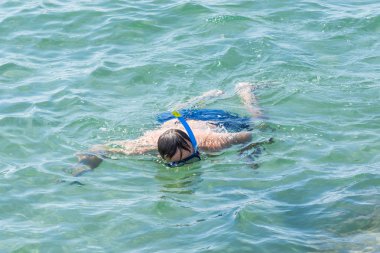 Side, Türkiye - 02 Haziran 2018: Mavi şortlu adam deniz yüzeyinde maske ve şnorkelle yüzerek en altta manzaranın keyfini çıkarıyor.