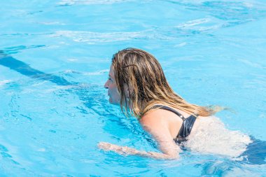 Side, Turkey - 2 Haziran 2018: Mayogiyen kız mavi havuzda yüzüyor.