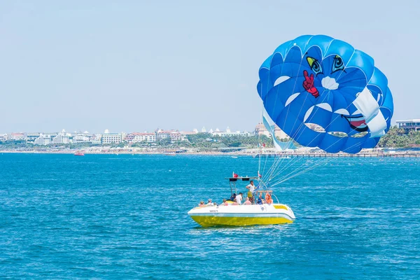 SIDE, TURKEY - JUNE 02, 2018: Blue parachute with tourists rises into sky from speed of boat speeding through blue sea. — Stock Photo, Image