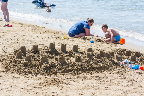 LADO, TURQUÍA - 02 DE JUNIO DE 2018: Mamá y el niño construyeron castillo de arena de cubo en la orilla del mar . —  Fotos de Stock