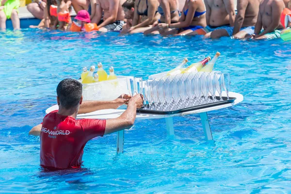 SIDE, TURKEY - ИЮНЬ 2, 2018: Мужчина-бармен расставляет бутылки и стаканы на столе в голубом бассейне . — стоковое фото