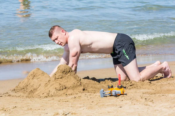 СИДЕ, ТУРЦИЯ - 02 ИЮНЯ 2018 г.: Человек в шортах строит песчаный замок на пляже . — стоковое фото