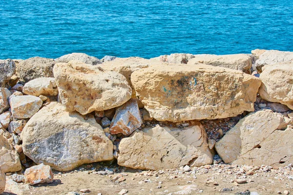 Sahil mavi deniz yakınında keskin taşlarla döşenmiştir.