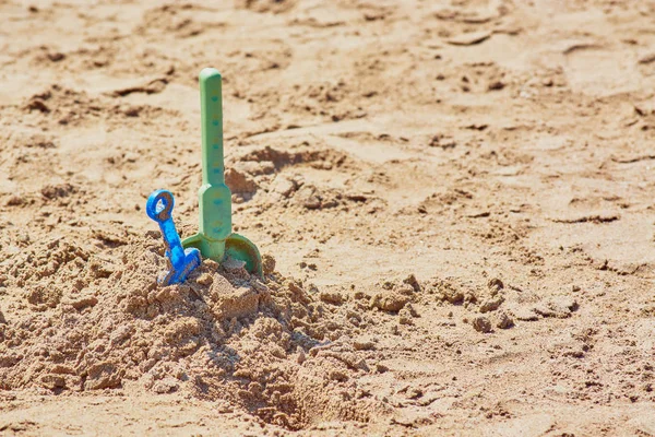 Baby shovels stuck in sand on sandy shore of beach. — Stock Photo, Image