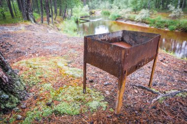 Ormanda taiga nehri arka planda şiş kebap için boş paslı brazier.