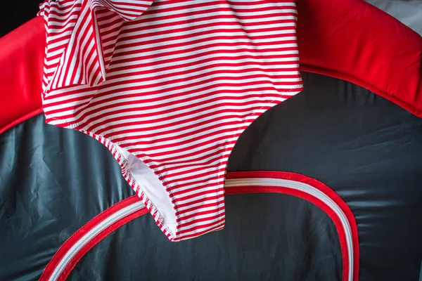 Женский купальник в красных полосках висит на детской кровати . — стоковое фото
